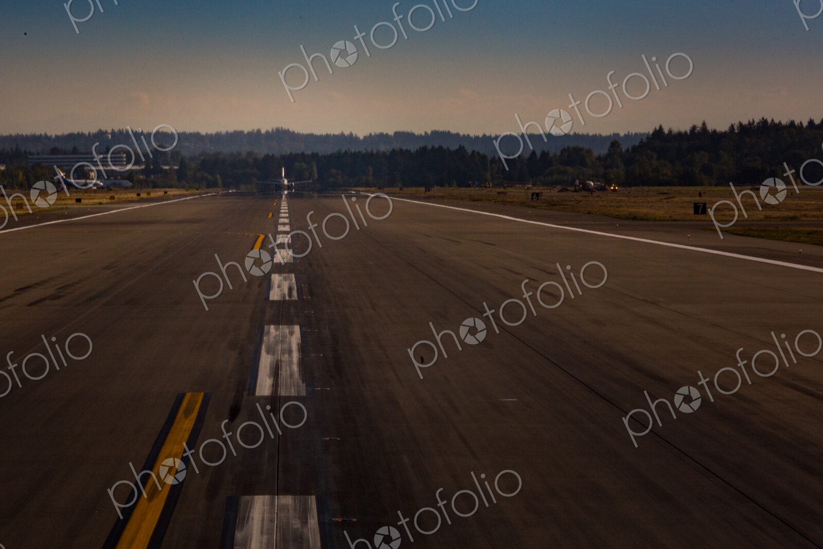 View down an airport runway, an aircraft preparing for take off.