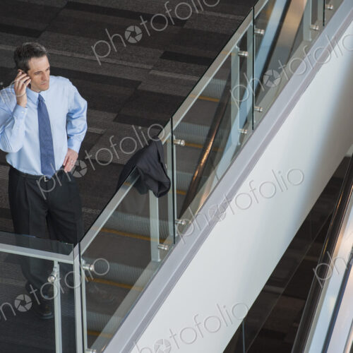 View from above looking down on a businessman using his phone in a conference centre…