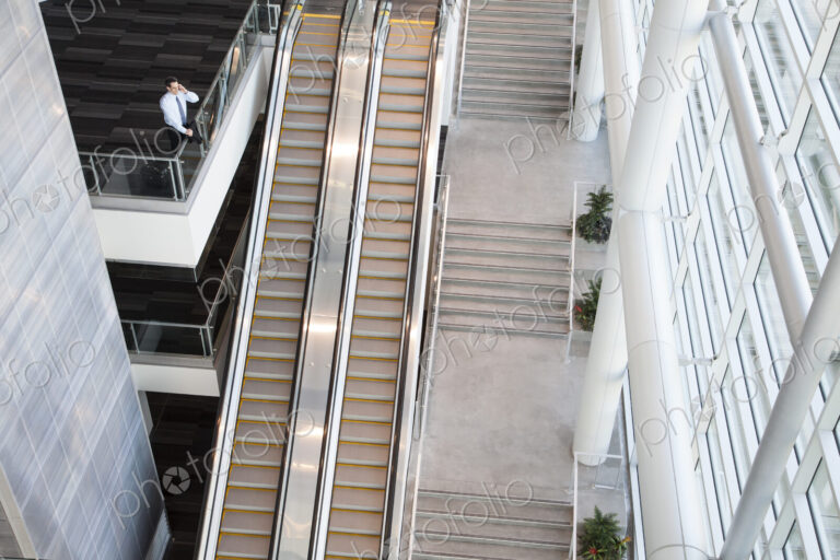 View from above looking down on a businessman using his phone in a conference centre…
