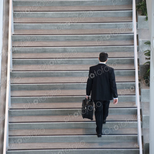View from above looking down on a businessman walking up stairs in a conference centre… View from above looking down on a businessman walking up stairs in a conference centre…