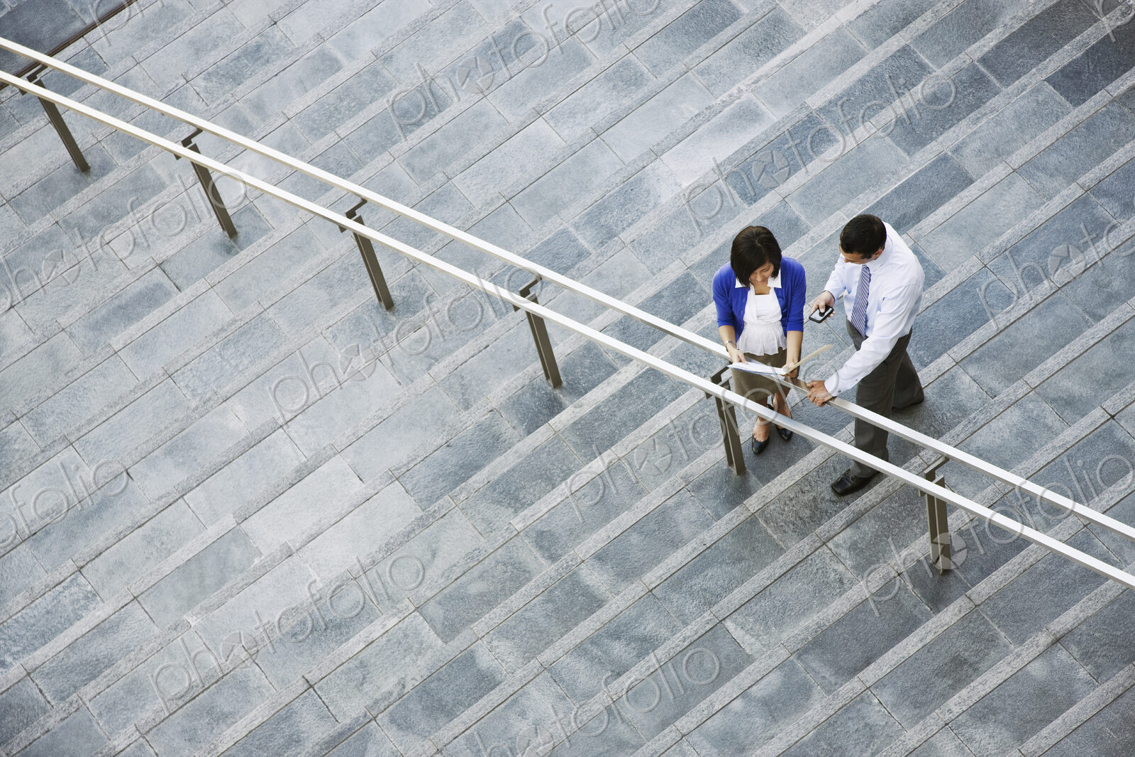 View from above looking down on a businesswoman and businessman standing on steps up…