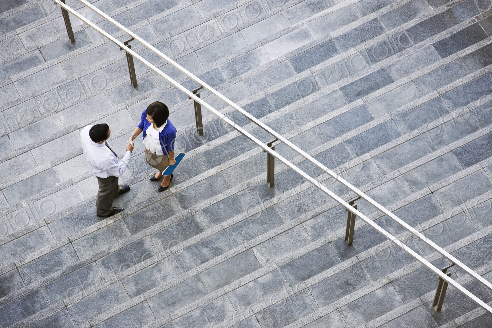 View from above looking down on a businesswoman and businessman standing on steps up…