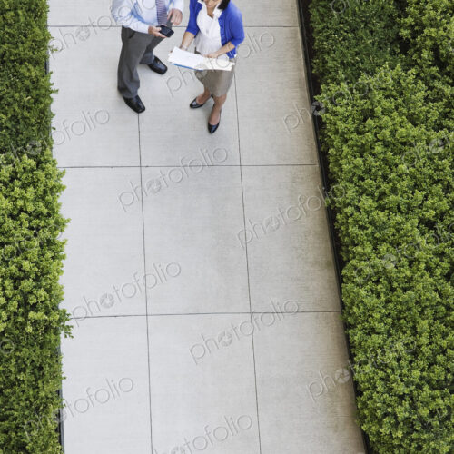 View from above of a businessman and woman looking at paperwork while standing on a…