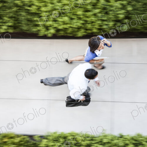 View from above of a businessman and woman walking on a sidewalk. View from above of a businessman and woman walking on a sidewalk.