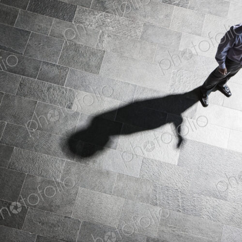 View from above of a businessman checking his phone and his shadow on the lobby floor. View from above of a businessman checking his phone and his shadow on the lobby floor.