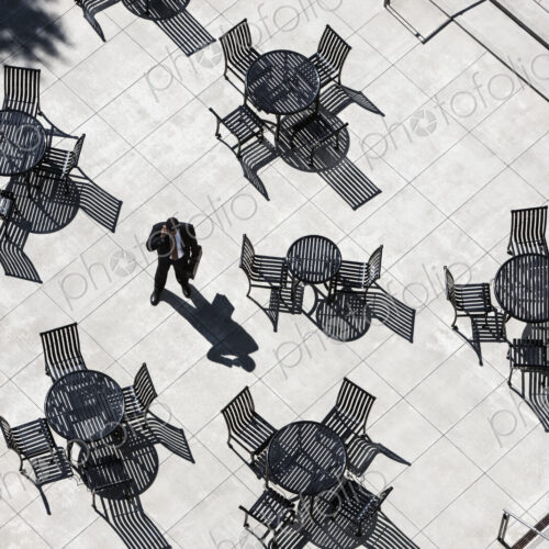 View from above of a businessman on his phone standing on a cafe terrace. View from above of a businessman on his phone standing on a cafe terrace.