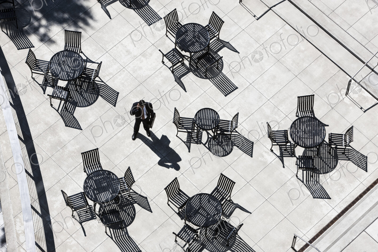 View from above of a businessman on his phone standing on a cafe terrace.