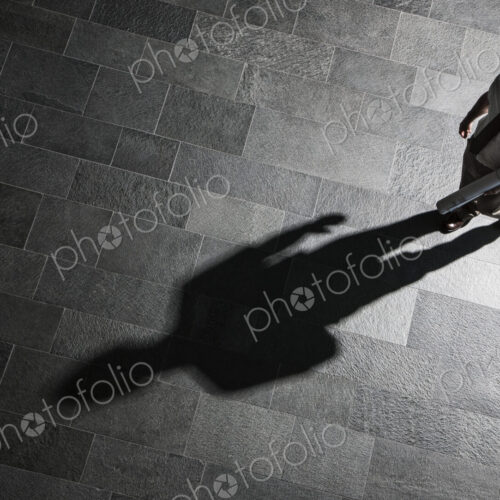 View from above of a businessman walking across a lobby floor and a shawdow on the floor. View from above of a businessman walking across a lobby floor and a shawdow on the floor.