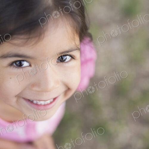 View from above of a child, a girl with dark brown hair and brown eyes.