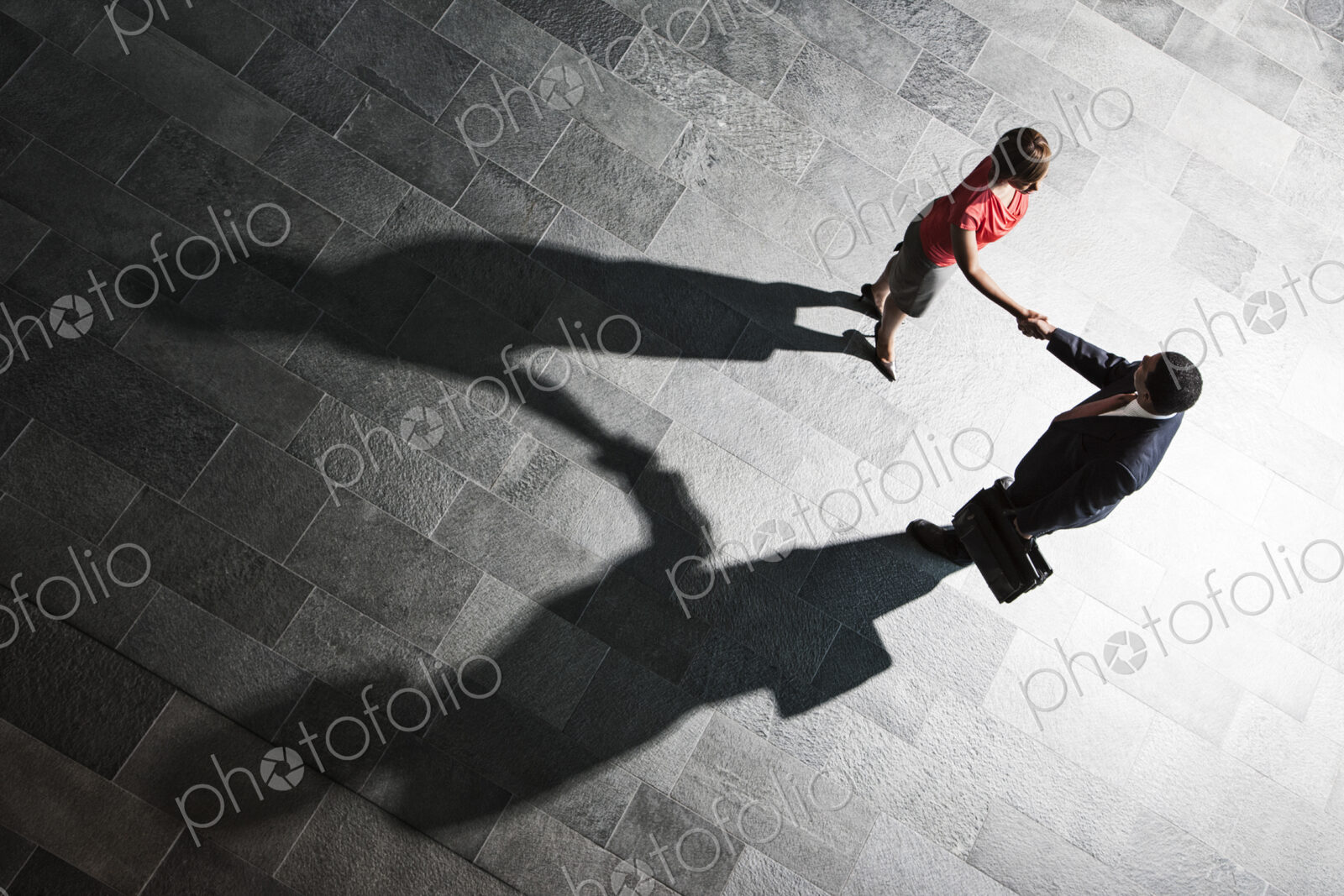 View from above of a handshake and shadows between a businessman and business woman.
