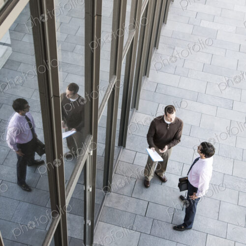 View from above of two businessmen meeting outside of a building next to a bank of… View from above of two businessmen meeting outside of a building next to a bank of…