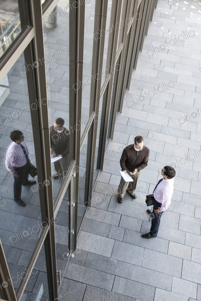 View from above of two businessmen meeting outside of a building next to a bank of…
