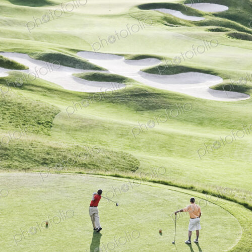 View from above of two golfer teeing off on a golf course. View from above of two golfer teeing off on a golf course.