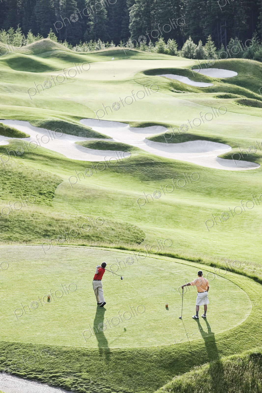 View from above of two golfer teeing off on a golf course.