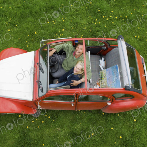 View from above of two people, a couple in a car with the roof open. View from above of two people, a couple in a car with the roof open.