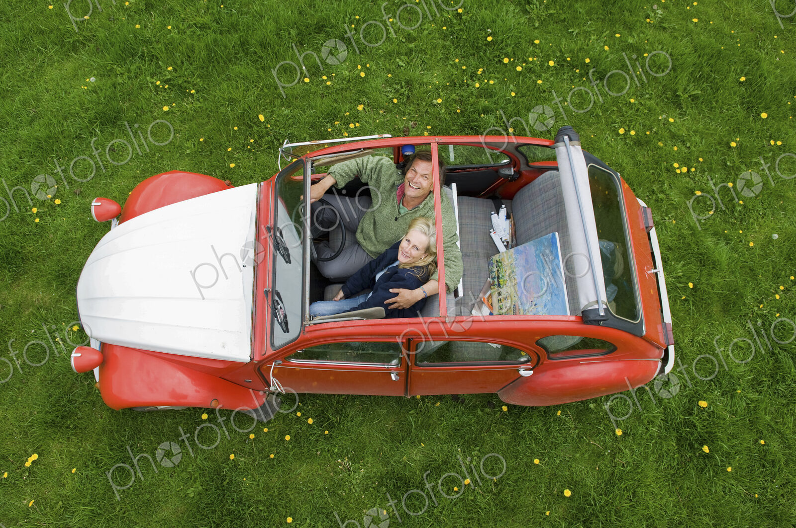 View from above of two people, a couple in a car with the roof open.