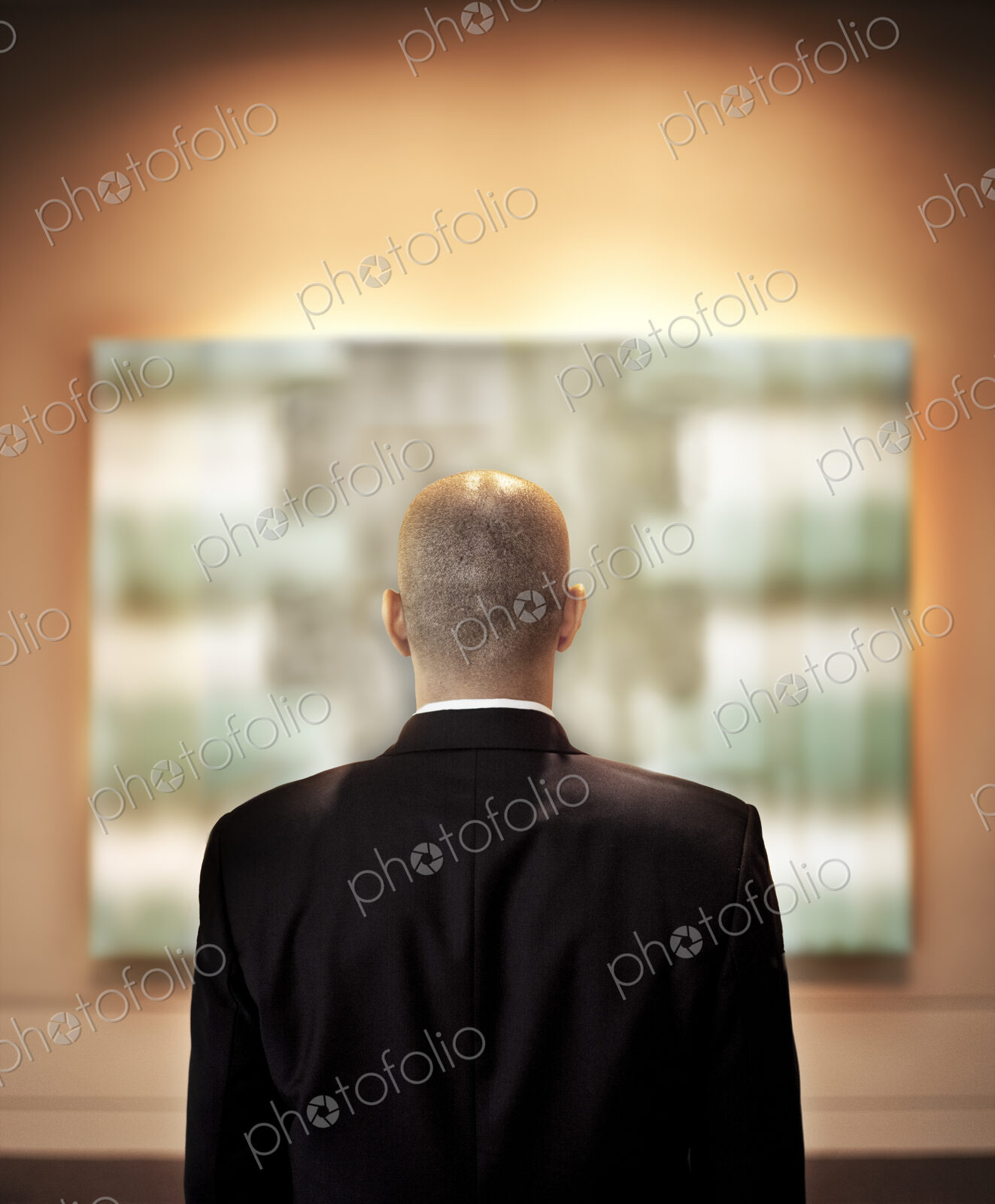 View from behid of a businessman looking at a piece of art in a gallery.