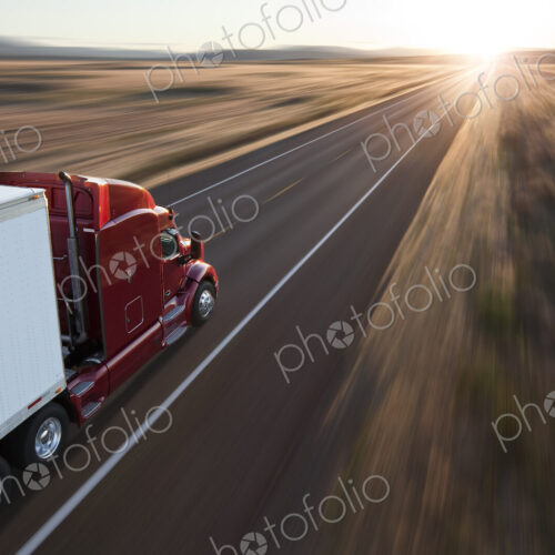 View from behind and above a commercial truck on the road at sunset on a highway in… View from behind and above a commercial truck on the road at sunset on a highway in…