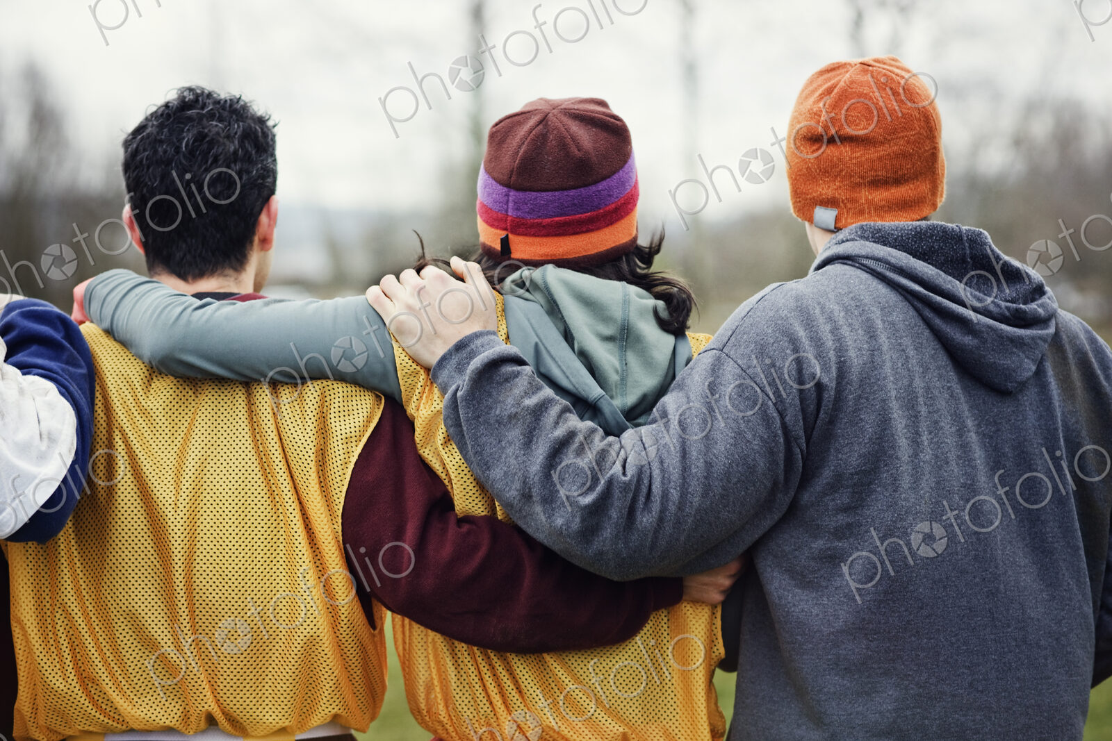 View from behind of three friends with their arms around one another in sports kit and…