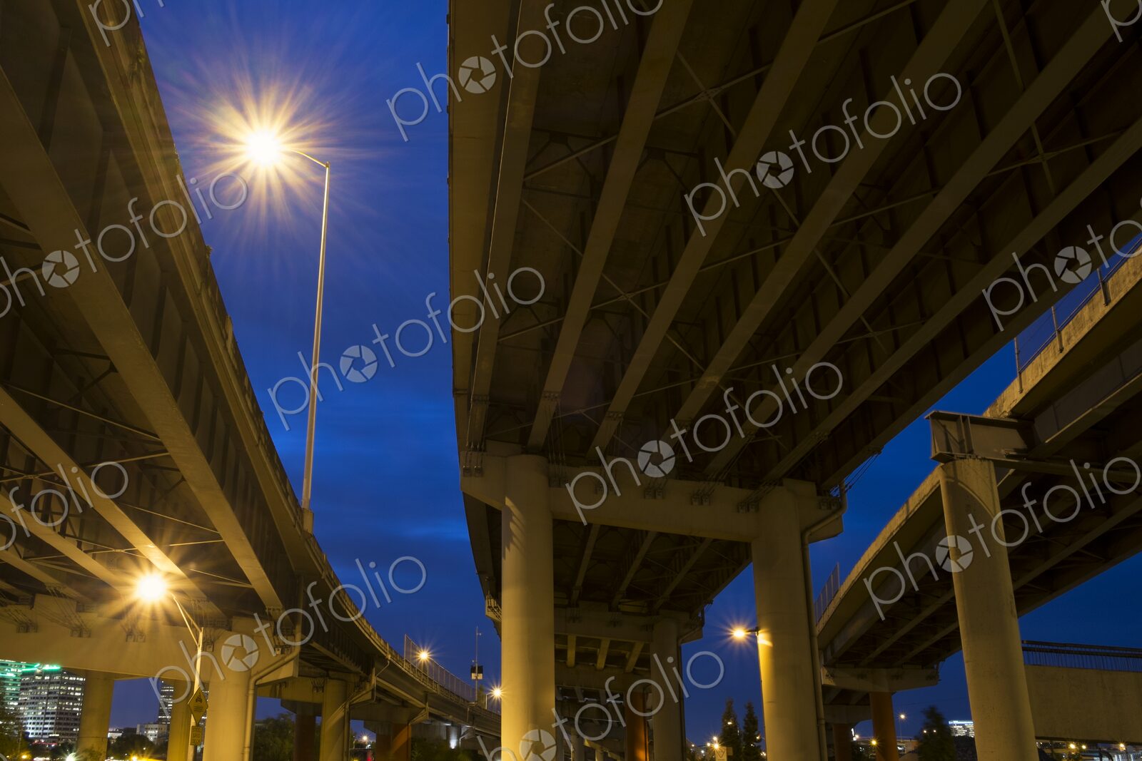 View from below of I-5 freeway overpass at night in Portland, Oregon. Streetlights…