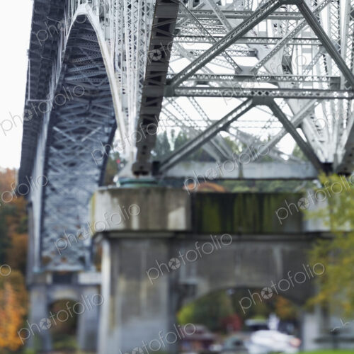View from below of a metal structure, pillars and arch of bridge