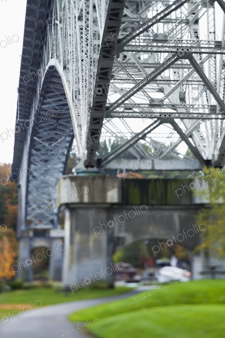 View from below of a metal structure, pillars and arch of bridge