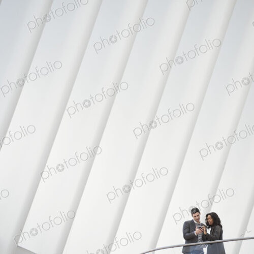 View from below of two people standing on a balcony in the Oculus building, floating… View from below of two people standing on a balcony in the Oculus building, floating…