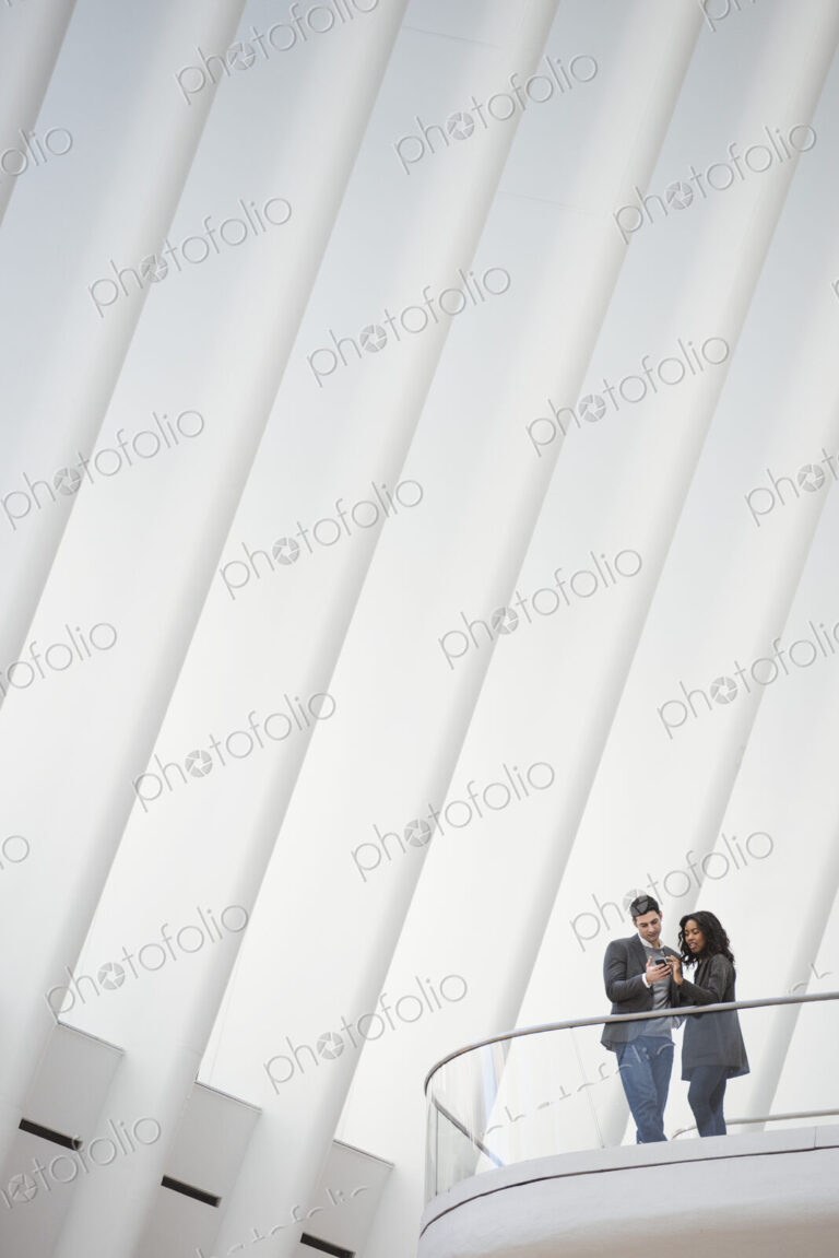 View from below of two people standing on a balcony in the Oculus building, floating…