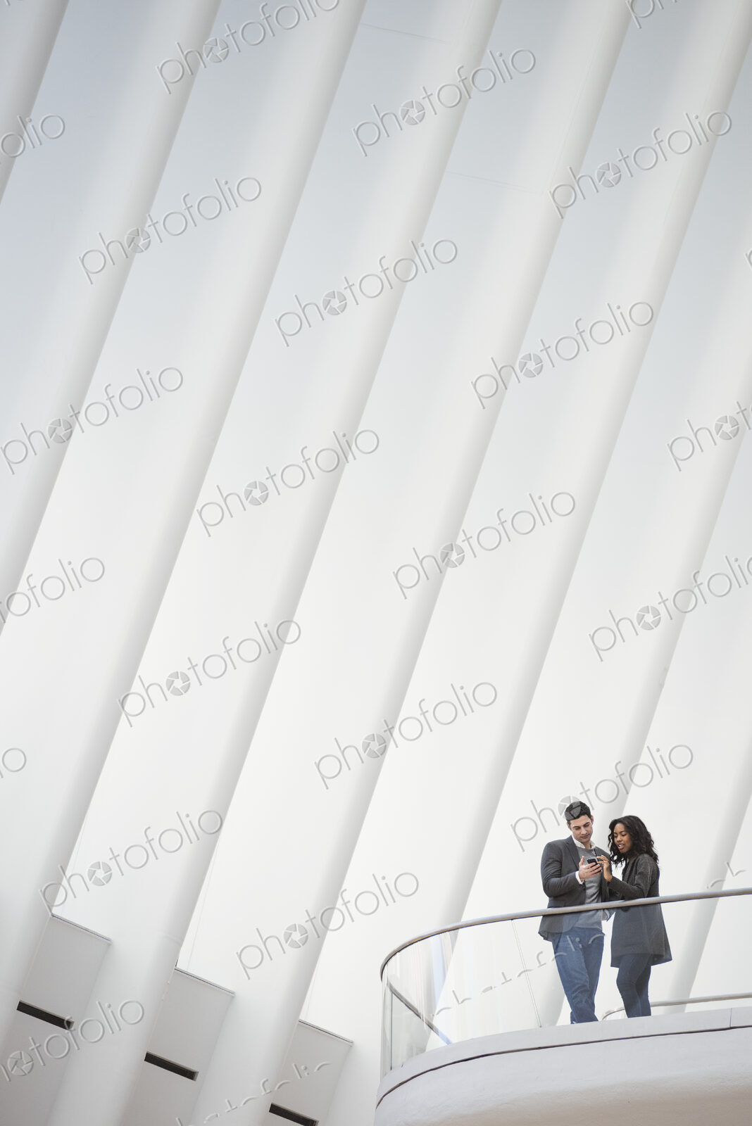 View from below of two people standing on a balcony in the Oculus building, floating…