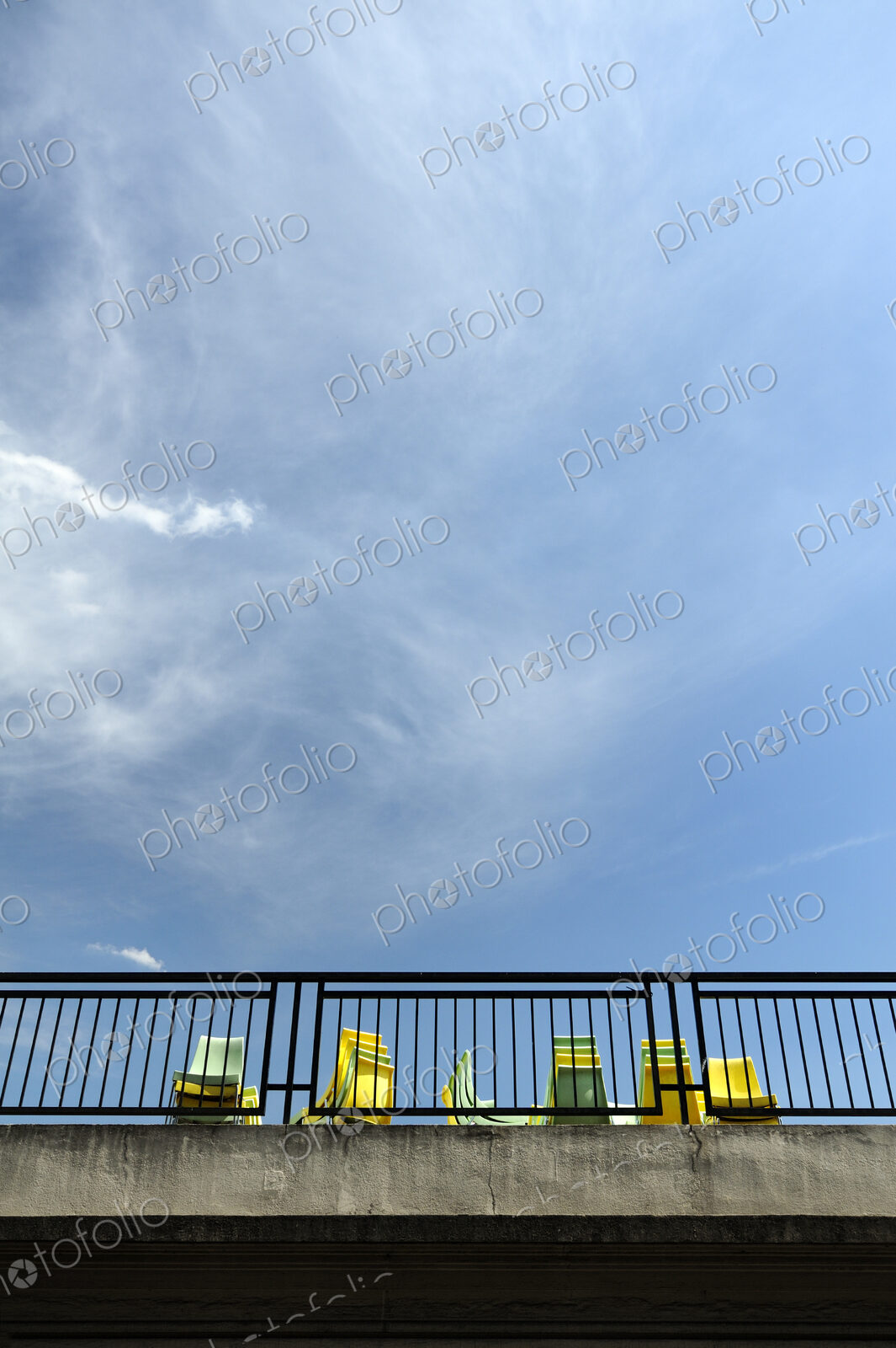 View from below of yellow and blue chairs on a terrace.