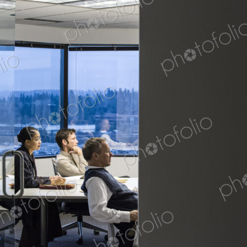 View from outside of a conference room looking in at a mixed race group of business… View from outside of a conference room looking in at a mixed race group of business…