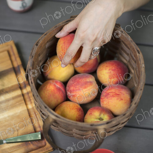 View from overhead of a picnic table with a basket of fresh peaches and a cheese board.