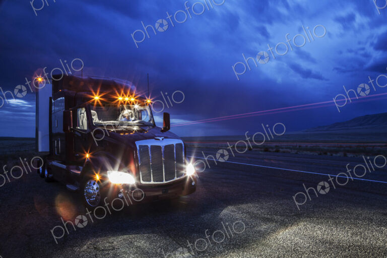 View into the cab of a commercial truck with a driver in the front seat at night.