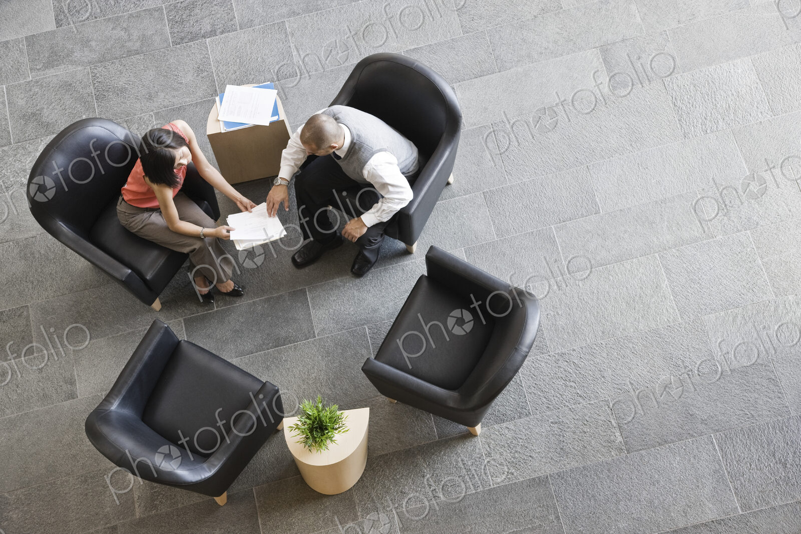View looking down on a businessman and businesswoman sitting and talking in office…