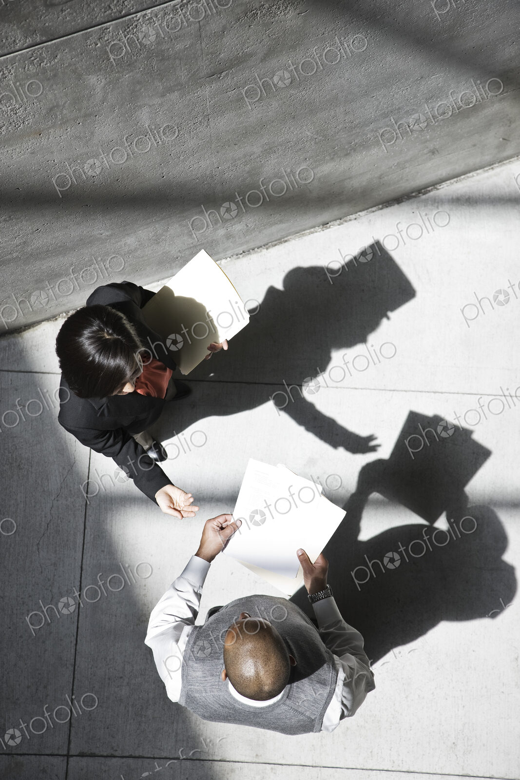 View looking down on a businesswoman and businessman talking in an office building lobby.
