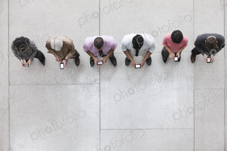 View looking down on a group of business people in a lobby area using their cell phones.