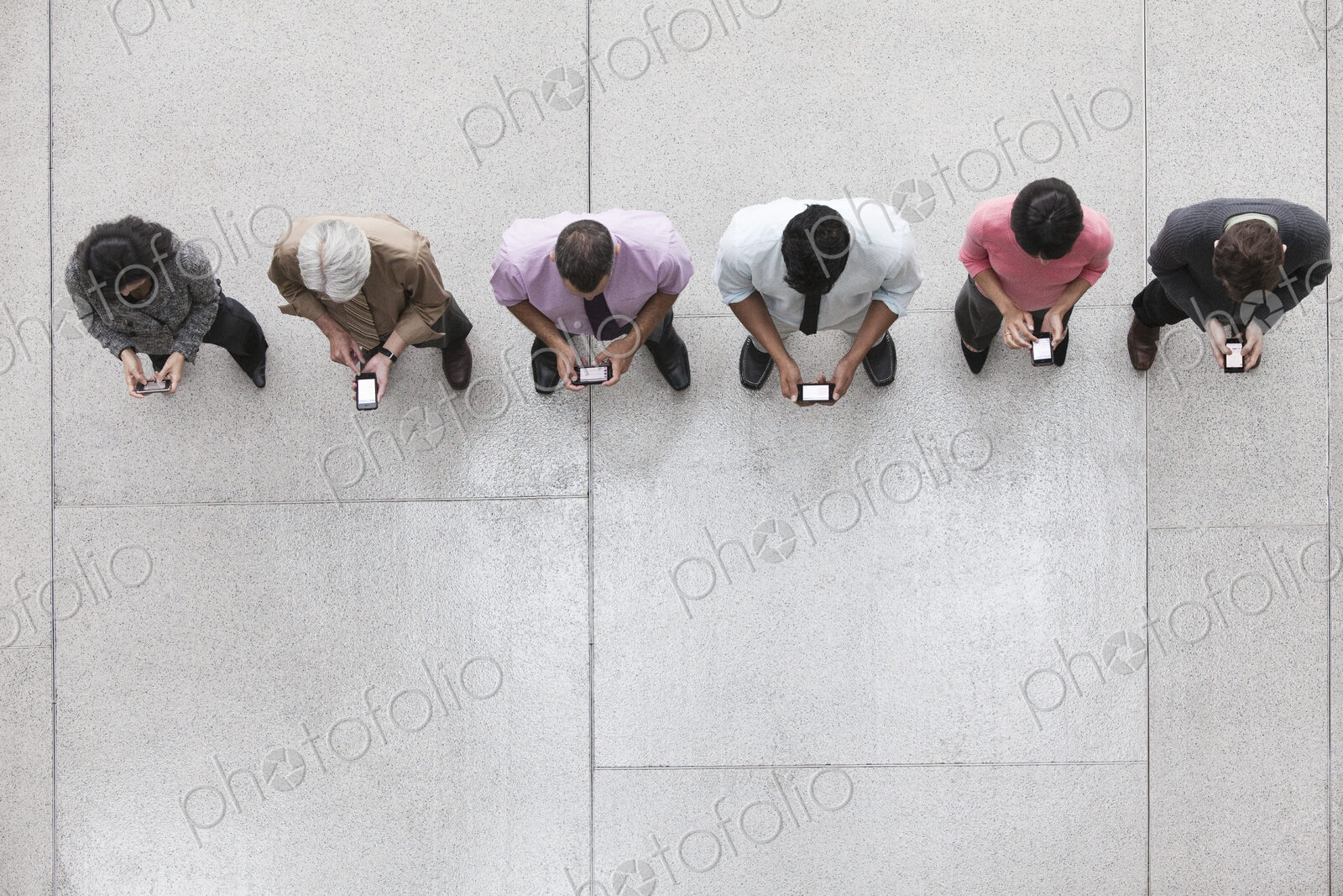 View looking down on a group of business people in a lobby area using their cell phones.
