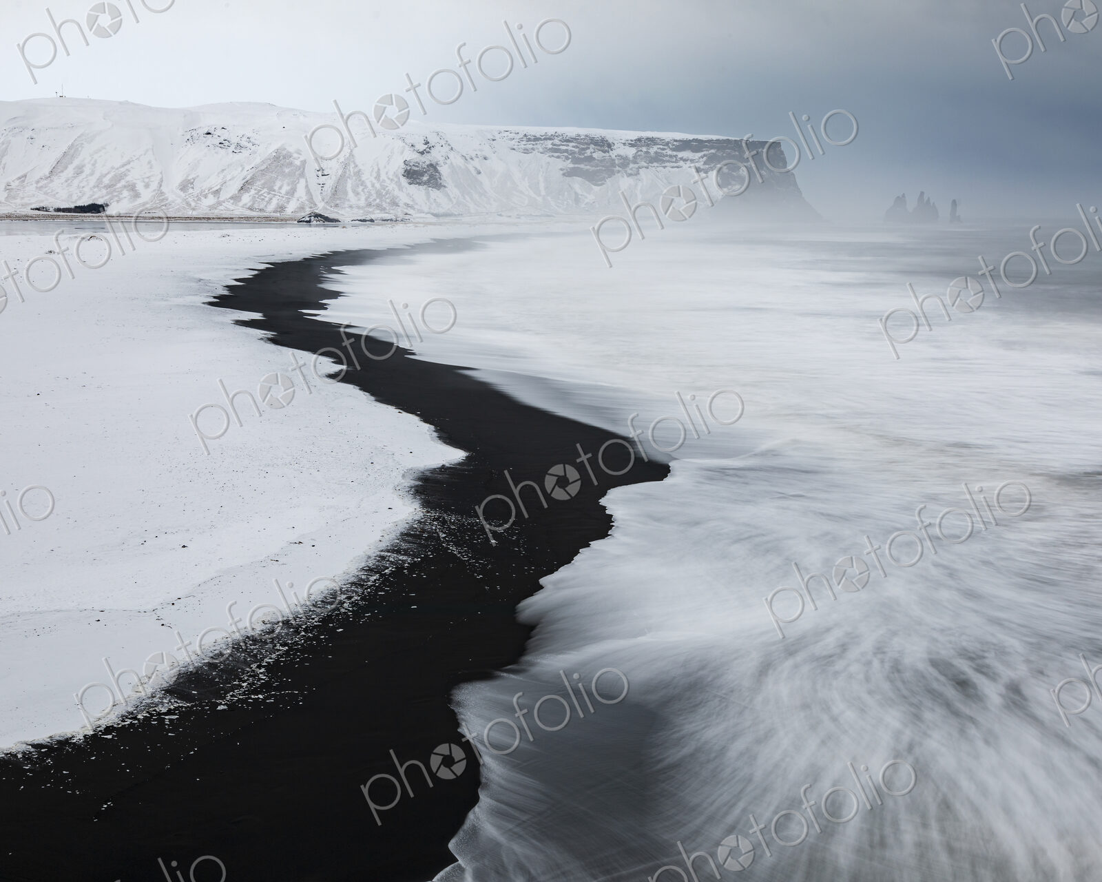 View of Reynisfjara Beach Looking towards Vik, a black sand beach, snow on the sand…