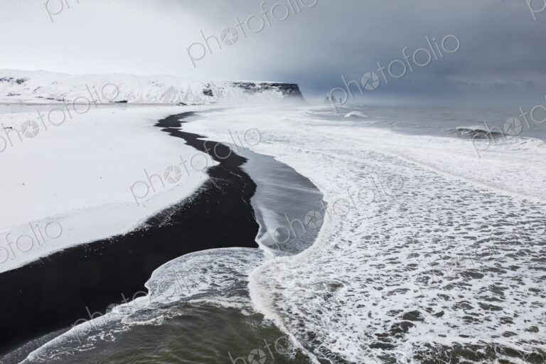 View of Reynisfjara Beach Looking towards Vik, a black sand beach, snow on the sand…