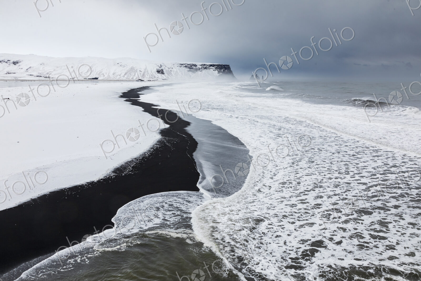View of Reynisfjara Beach Looking towards Vik, a black sand beach, snow on the sand…
