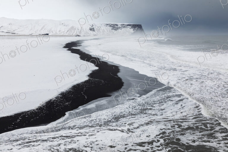 View of Reynisfjara Beach Looking towards Vik, a black sand beach, snow on the sand…