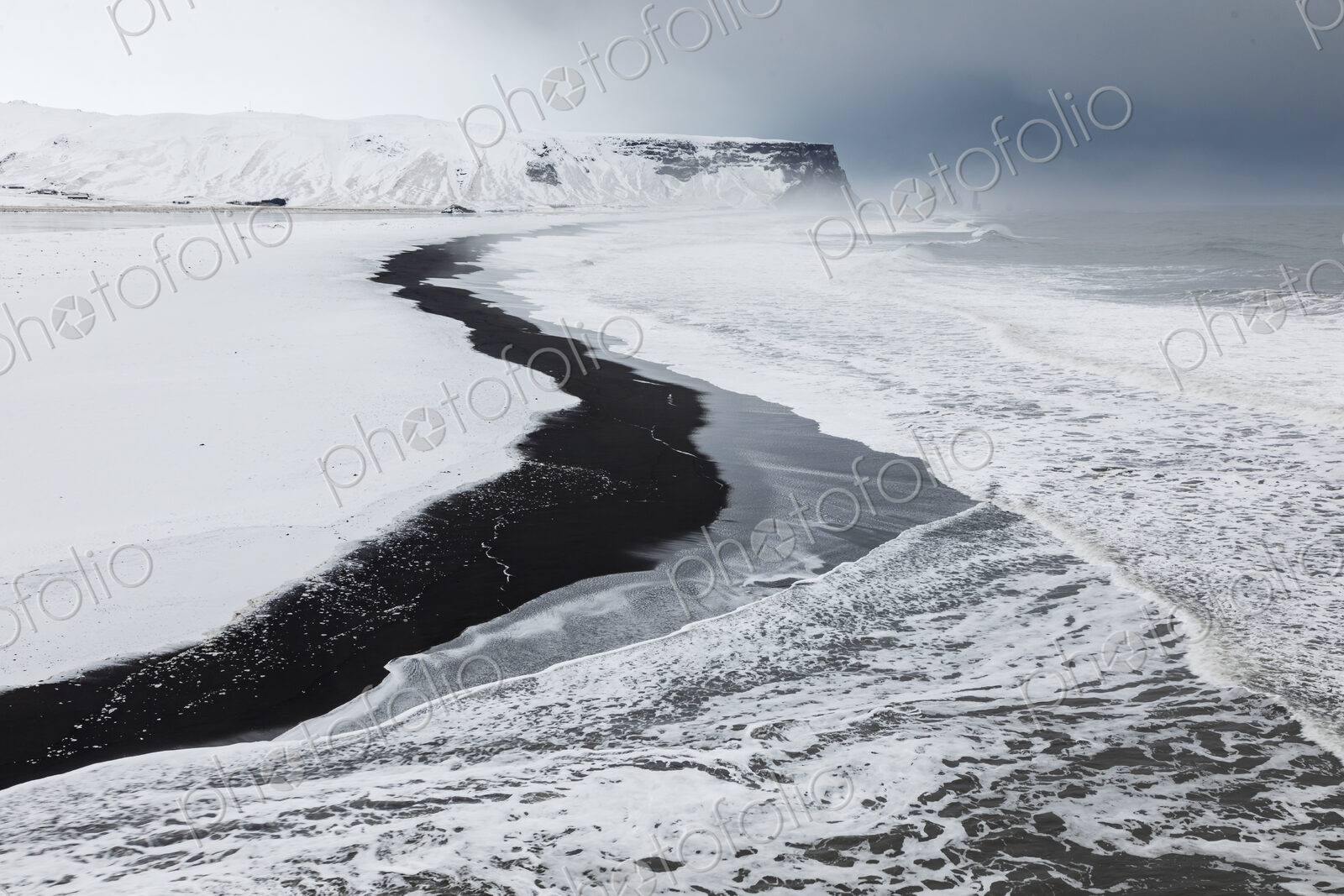 View of Reynisfjara Beach Looking towards Vik, a black sand beach, snow on the sand…