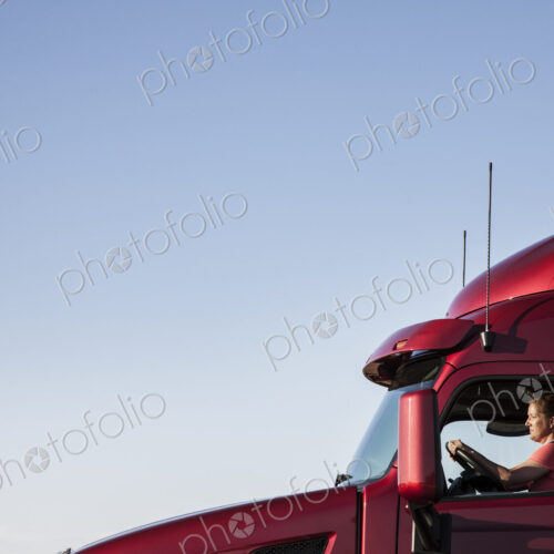 View of a Caucasian woman driver in the cab of her commercial truck. View of a Caucasian woman driver in the cab of her commercial truck.