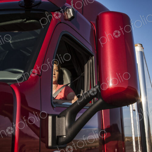 View of a Caucasian woman driver in the cab of her commercial truck. View of a Caucasian woman driver in the cab of her commercial truck.