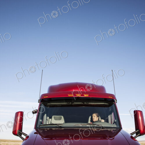 View of a Caucasian woman driver in the cab of her commercial truck. View of a Caucasian woman driver in the cab of her commercial truck.