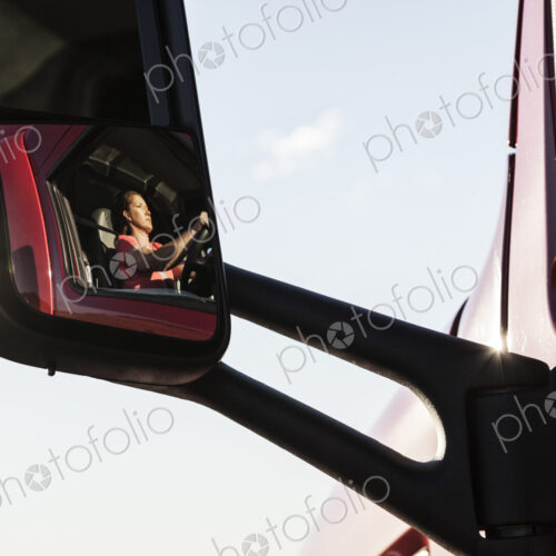 View of a Caucasian woman driver in the cab of her commercial truck. View of a Caucasian woman driver in the cab of her commercial truck.