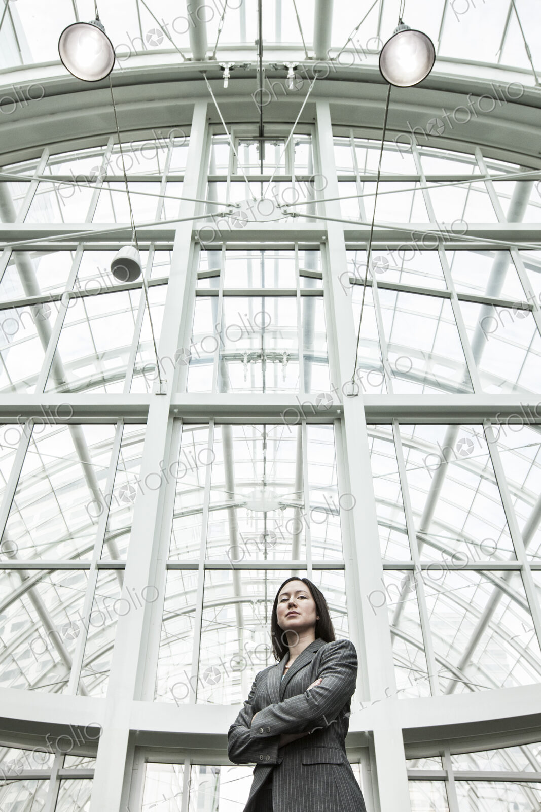 View of a caucasian business woman in a suit coat standing in a covered glass walkway.