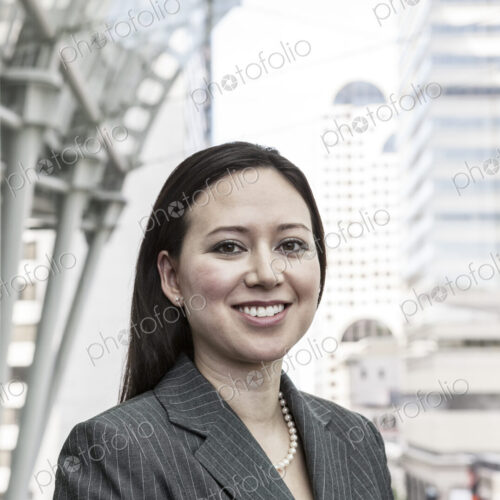 View of a caucasian business woman in a suit coat standing in a covered glass walkway.