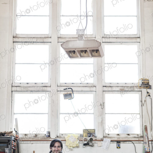 View of a caucasian man factory worker wearing safetly glasses in a woodworking factory.
