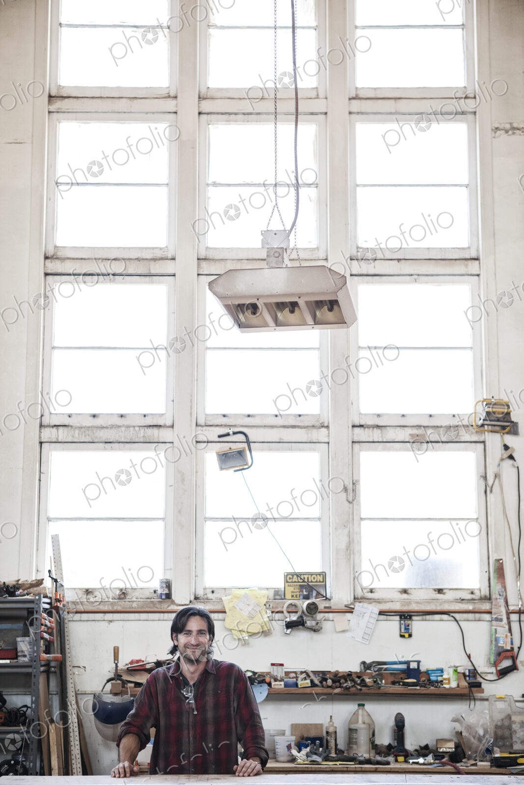View of a caucasian man factory worker wearing safetly glasses in a woodworking factory.